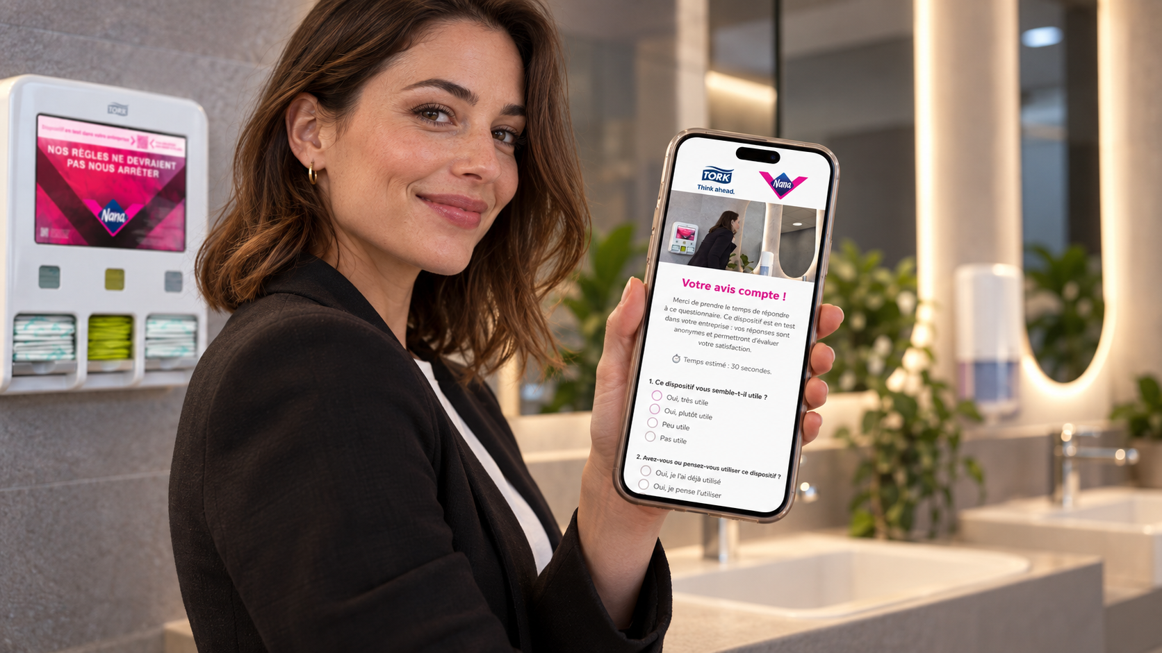 Collaboratrice consultant sur son mobile le questionnaire Tork x Nana dans un sanitaire